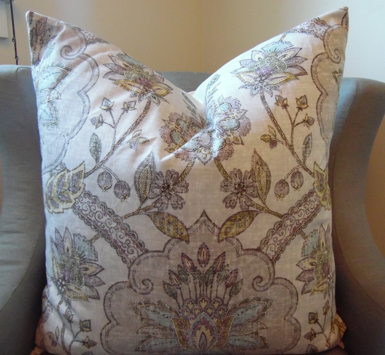 May include: A decorative cushion with a floral pattern in shades of beige, brown, purple, and blue. The cushion features a paisley design with intricate details.