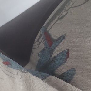 May include: A white pillow with a blue and red airplane design. The pillow is made of a soft, textured fabric.