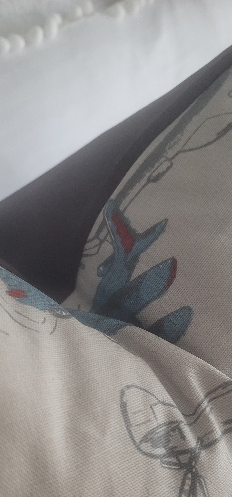 May include: A white pillow with a blue and red airplane design. The pillow is made of a soft, textured fabric.
