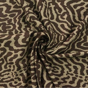 May include: Brown and beige fabric with a swirling, abstract animal print pattern.
