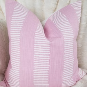 May include: A pink throw pillow with a white geometric pattern. The pattern is made up of horizontal lines and curves.