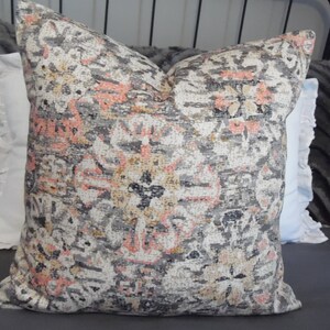 May include: A decorative throw pillow with a gray, pink, and beige floral pattern. The pillow is made of a soft, textured fabric.