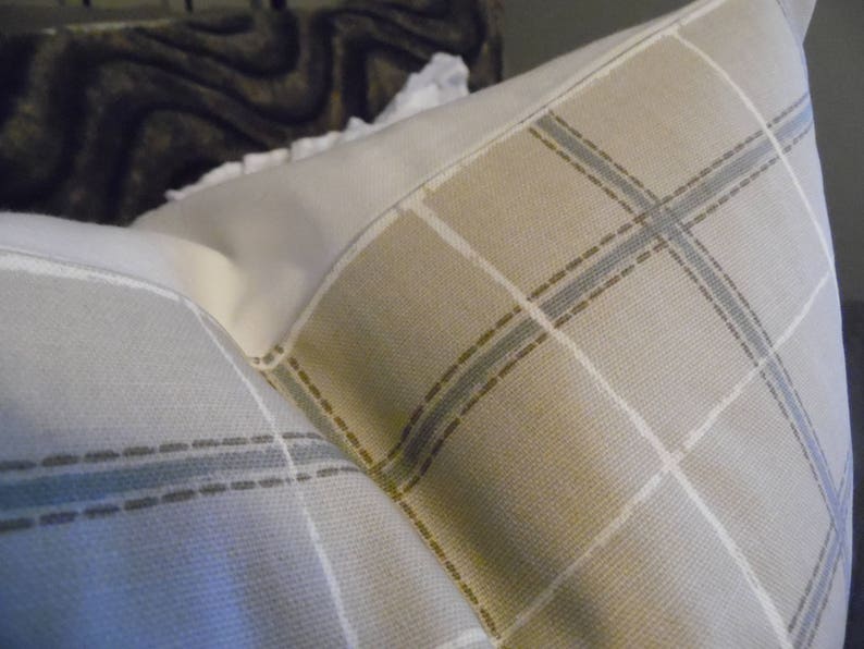 May include: Two pillowcases with a plaid pattern in shades of beige, brown, and blue. The pillowcases are made of a soft, woven fabric.