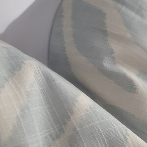 Puede incluir: Primer plano de una tela con estampado de color azul claro y blanco. La tela tiene un brillo sutil y una superficie texturizada.