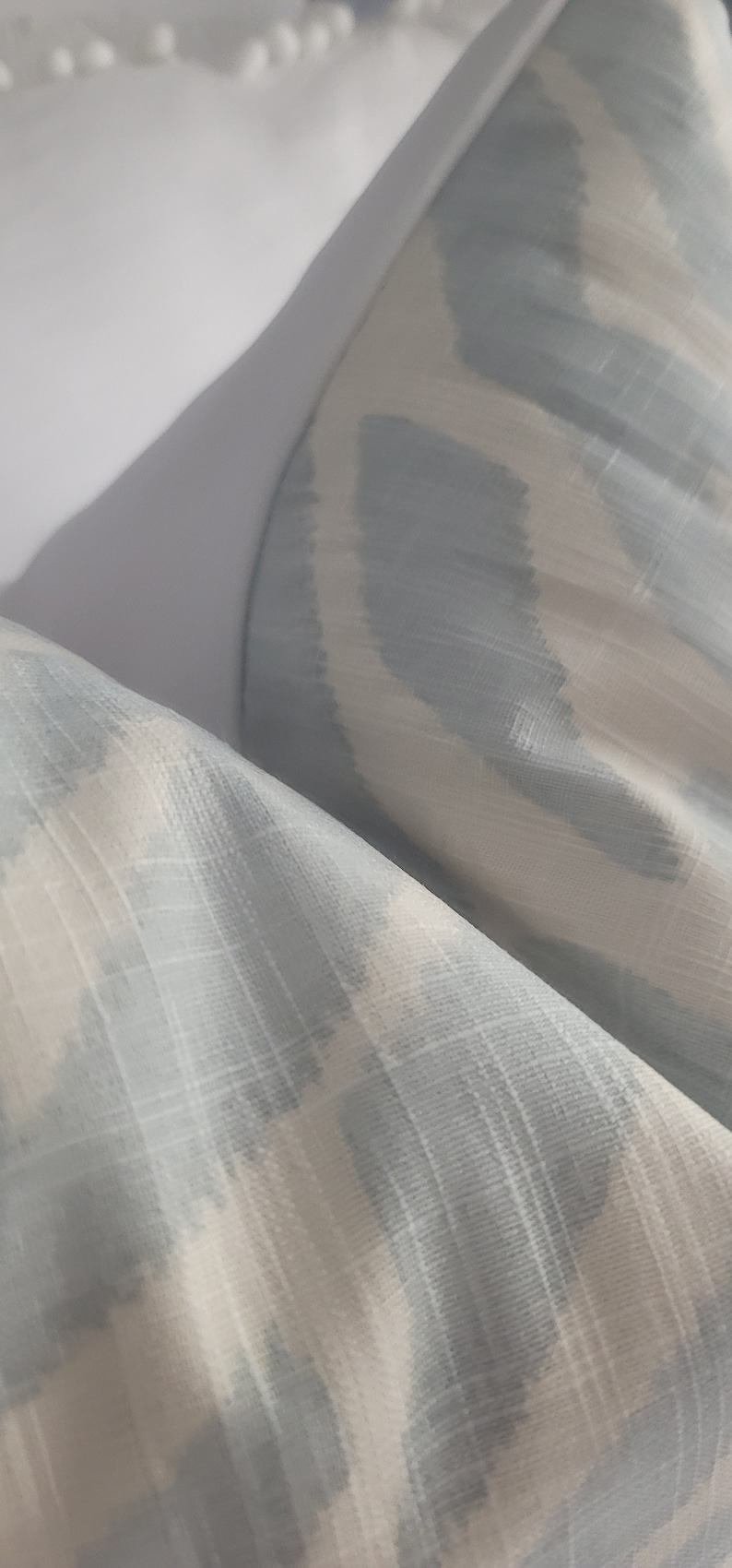 Puede incluir: Primer plano de una tela con estampado de color azul claro y blanco. La tela tiene un brillo sutil y una superficie texturizada.