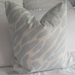 Puede incluir: Una almohada de tiro de color azul claro y blanco con un dise&ntilde;o de ikat sutil.
