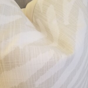 Puede incluir: Una almohada blanca con un sutil estampado de cebra marr&oacute;n claro. La tela tiene una textura similar al lino.