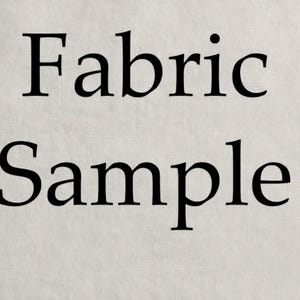 May include: A light beige fabric swatch featuring a visible woven texture. The words Fabric Sample are printed in large, bold, black serif font across the center of the material, clearly indicating that this is a textile material swatch.
