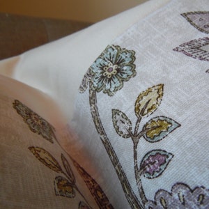 May include: A white fabric with a floral pattern featuring blue, brown, and purple flowers. The fabric has a subtle texture and a light, airy feel.