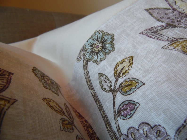 May include: A white fabric with a floral pattern featuring blue, brown, and purple flowers. The fabric has a subtle texture and a light, airy feel.