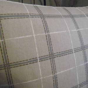 May include: A beige pillow with a light brown and gray plaid pattern.