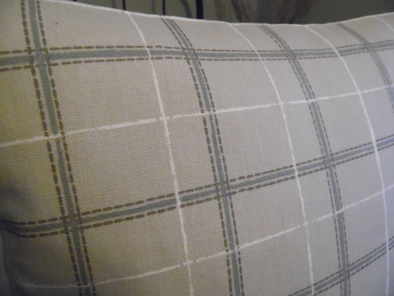 May include: A beige pillow with a light brown and gray plaid pattern.