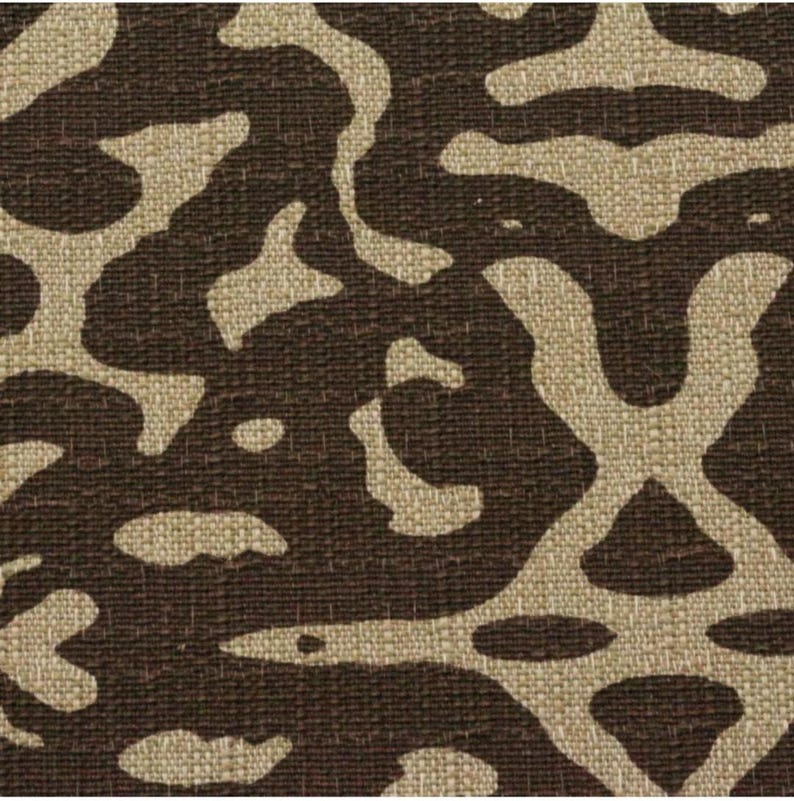 May include: A brown fabric with a beige abstract pattern. The pattern resembles a camouflage design.