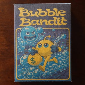 May include: A rectangular box with the words "Bubble Bandit" in yellow, stylized font. The box features cartoon illustrations of a blue bubble with a face and a yellow character holding a money bag and a wrench, surrounded by bubbles.