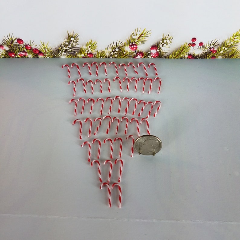 May include: A collection of miniature candy canes arranged in a heart shape. The candy canes are red and white and are approximately the size of a US quarter.