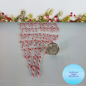 May include: A collection of 30 miniature candy canes, approximately 1 inch in length, arranged in a triangular shape. The candy canes are red and white striped. A US dime is included for scale.