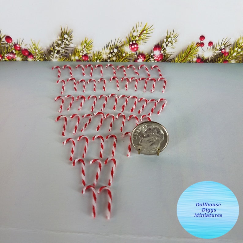 May include: A collection of 30 miniature candy canes, approximately 1 inch in length, arranged in a triangular shape. The candy canes are red and white striped. A US dime is included for scale.