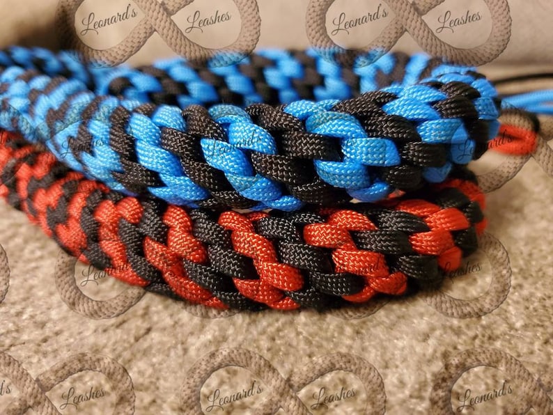 May include: Close-up of two braided dog leads. One is red and black, the other is blue and black. The leads are made of a durable material and are tightly woven. The brand name "Leonard's Leashes" is visible in the background.