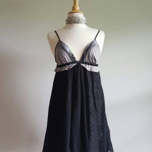 K&ouml;nnte beinhalten: Ein schwarzes Spitzenkleid mit einem grauen und schwarzen Samt-Oberteil. Das Kleid hat einen V-Ausschnitt und Spaghetti-Tr&auml;ger.