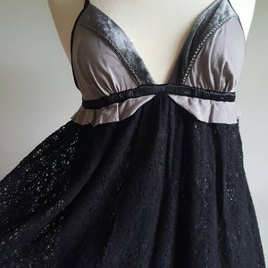 K&ouml;nnte beinhalten: Ein schwarzes Spitzenkleid mit einem grauen und samtenen Oberteil. Das Oberteil hat einen V-Ausschnitt und einen R&uuml;schenbesatz.