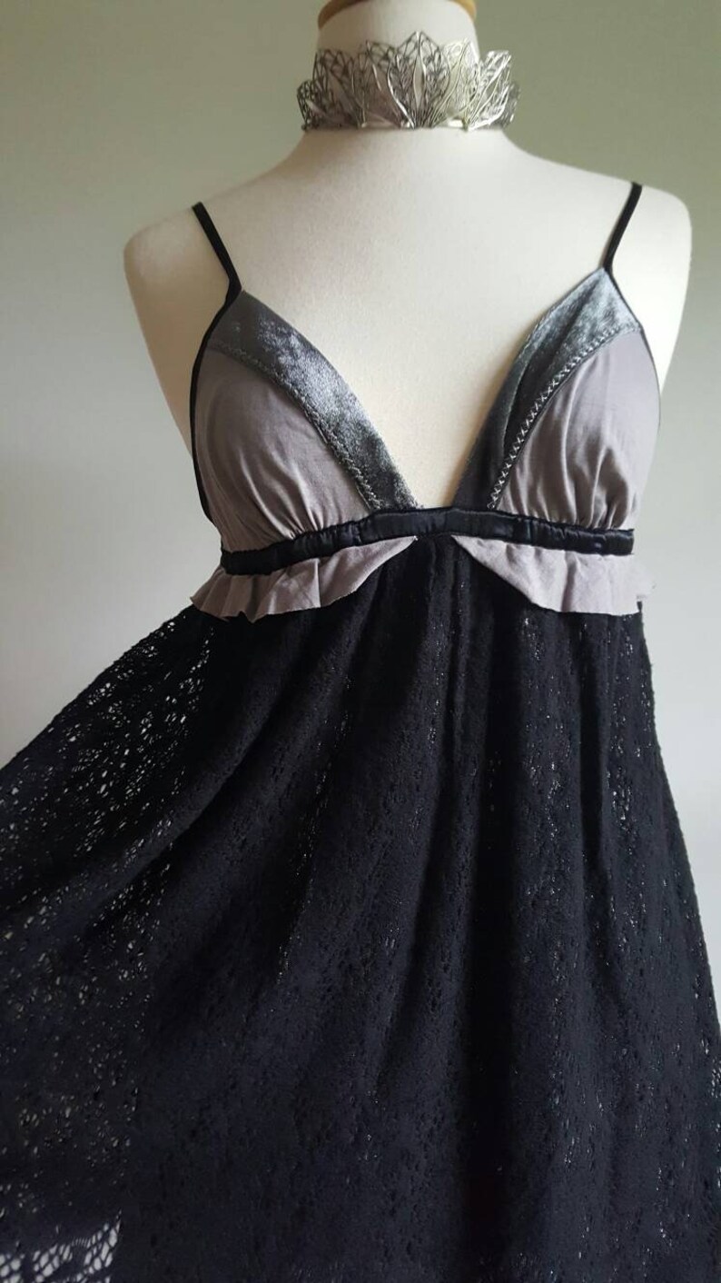 K&ouml;nnte beinhalten: Ein schwarzes Spitzenkleid mit einem grauen und samtenen Oberteil. Das Oberteil hat einen V-Ausschnitt und einen R&uuml;schenbesatz.