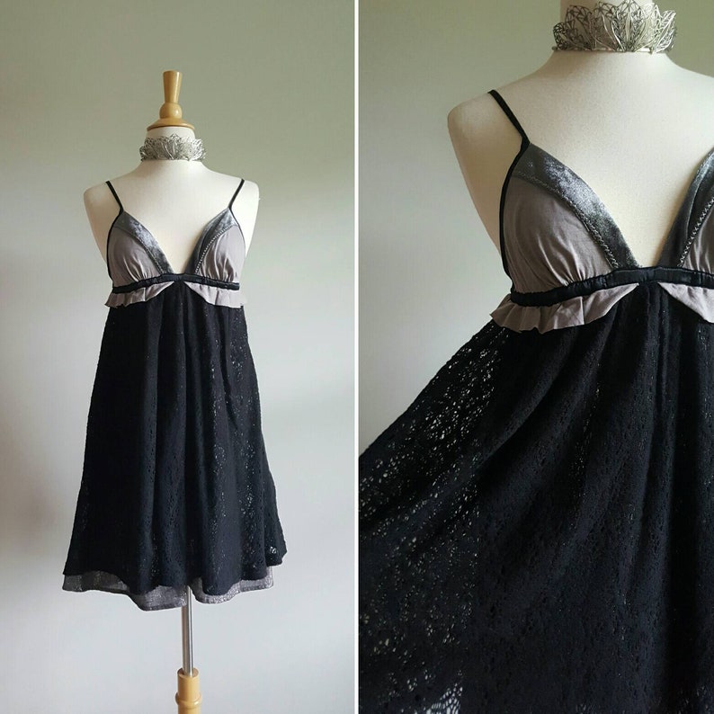 K&ouml;nnte beinhalten: Ein schwarzes Spitzenkleid mit einem grauen und schwarzen Samt-Oberteil. Das Kleid hat einen R&uuml;schenbesatz und ein tailliertes Oberteil.