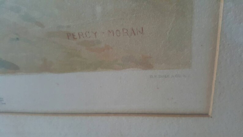 Puede incluir: Un primer plano de una obra de arte enmarcada con la firma del artista "Percy Moran" en tinta roja. La obra de arte est&aacute; sobre un fondo blanco con un passe-partout marr&oacute;n claro.