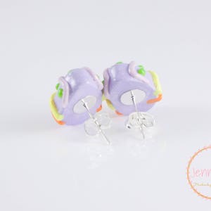 K&ouml;nnte beinhalten: Ein Paar violette und gelbe Polymer Clay Ohrringe in Form eines Kuchens mit Zuckerguss und Streuseln. Die Ohrringe haben silberne Ohrstecker.