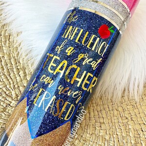 Puede incluir: Un vaso de glitter azul y dorado con el texto "La influencia de un gran maestro nunca se puede borrar".