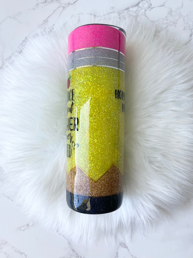 Puede incluir: Un vaso amarillo con purpurina con un dise&ntilde;o de l&aacute;piz negro y dorado. El vaso tiene una tapa rosa y el texto "Once a teacher, always a teacher" est&aacute; impreso en el lateral.
