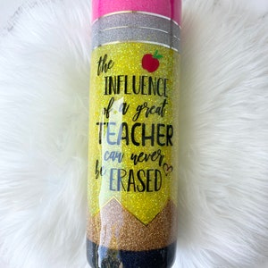 Puede incluir: Un vaso de glitter amarillo y negro con una tapa rosa. El vaso tiene un dise&ntilde;o de l&aacute;piz y el texto "the INFLUENCE of a great TEACHER can never be ERASED".