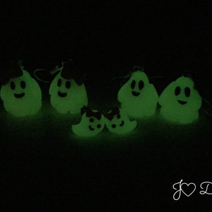 May include: A set of five glow-in-the-dark ghost ornaments with smiling faces. The ghosts are made of a white material and have a green glow. The ornaments are perfect for Halloween decorations.