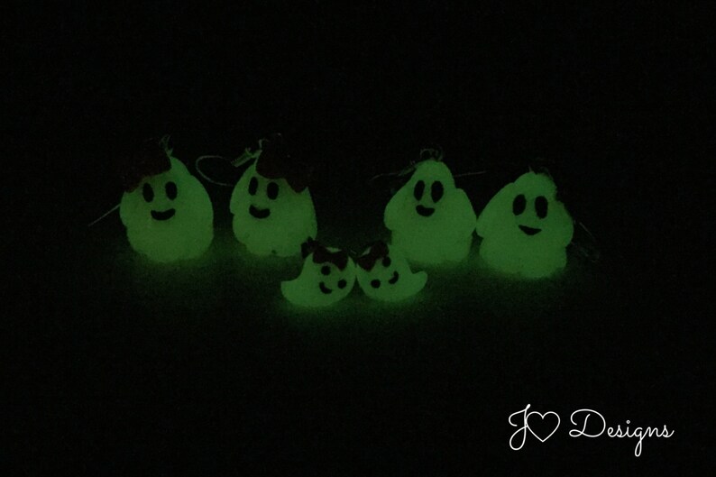 May include: A set of five glow-in-the-dark ghost ornaments with smiling faces. The ghosts are made of a white material and have a green glow. The ornaments are perfect for Halloween decorations.