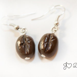 May include: A pair of silver earrings with brown coffee bean charms.