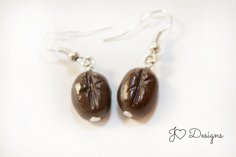 May include: A pair of silver earrings with brown coffee bean charms.