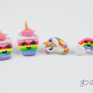 May include: A set of five colorful clay earrings featuring a rainbow cupcake, a unicorn, and a rainbow with clouds. Each earring has a cute, smiling face.