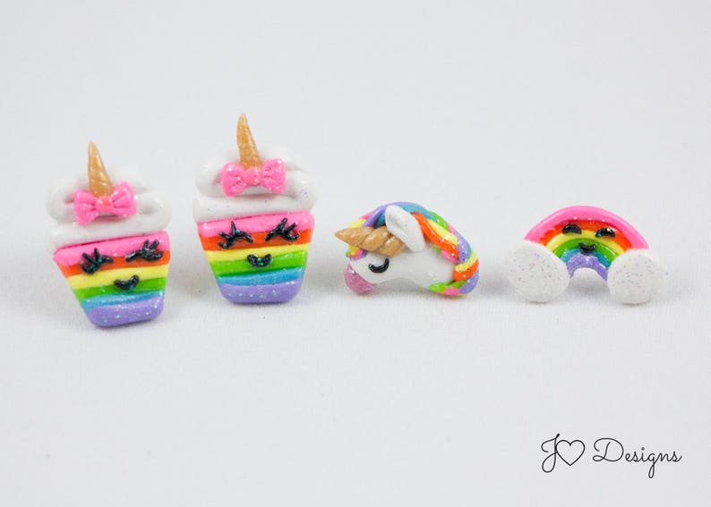 May include: A set of five colorful clay earrings featuring a rainbow cupcake, a unicorn, and a rainbow with clouds. Each earring has a cute, smiling face.