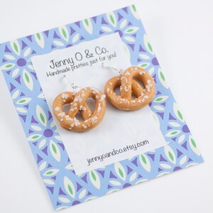 Puede incluir: Un par de pendientes de pretzel en una tarjeta con estampado azul y blanco con el texto "Jenny O & Co. Handmade pretties just for you! jennyoandco.etsy.com"
