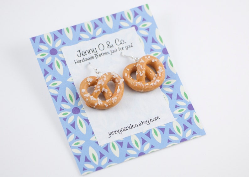 Puede incluir: Un par de pendientes de pretzel en una tarjeta con estampado azul y blanco con el texto "Jenny O & Co. Handmade pretties just for you! jennyoandco.etsy.com"