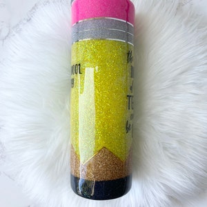 Puede incluir: Un vaso amarillo con purpurina con un dise&ntilde;o de l&aacute;piz negro y dorado. El vaso tiene una tapa rosa y una banda plateada alrededor del medio. El texto en el vaso dice "La mejor parte de la ense&ntilde;anza es ser..."