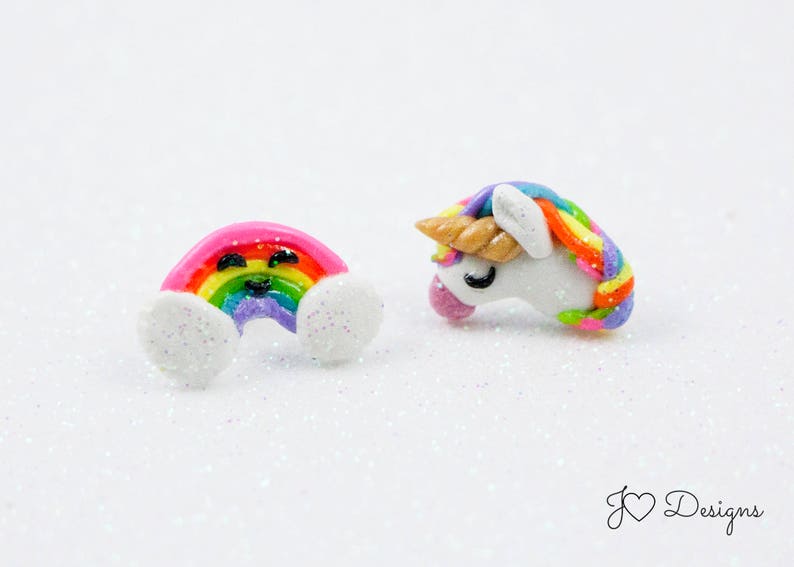 May include: A pair of colorful polymer clay earrings. One earring is a rainbow with a smiley face and the other is a white unicorn with a rainbow mane.