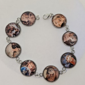 Op de afbeelding: Een zilveren armband met zeven ronde bedels met afbeeldingen van personages uit de film Labyrinth. De bedels zijn met elkaar verbonden door een zilveren ketting.
