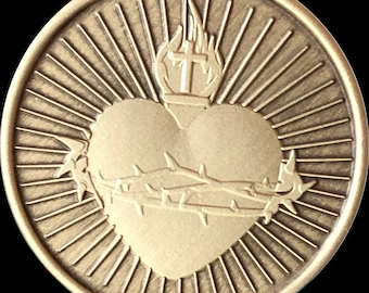May include: A gold-coloured metal medallion featuring a raised image of a heart pierced by a crown of thorns. The heart is surrounded by a radiating sunburst pattern.