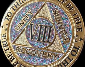 May include: Gold-colored coin with a glittery surface and the inscription "Be True To Thine Own Self Be True To Thine Own Self" around the edge. The center of the coin features a triangle with the words "Unity", "Service", and "Recovery" inscribed on each side. The number "VIII" is in the center of the triangle.