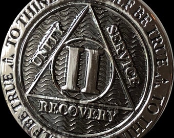 May include: Silver-toned metal coin with a triangle design featuring the words "Unity", "Service", and "Recovery". The number "II" is in the center of the triangle. The coin has the text "To thine own self be true" around the edge.