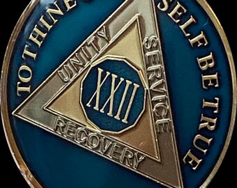May include: A gold and blue sobriety coin with the inscription "To thine own self be true" and a triangle with the words "Unity, Service, Recovery" and the number "XXII" in the centre.
