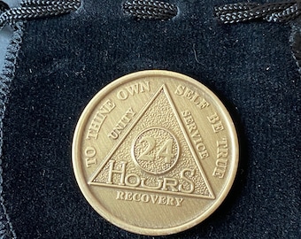 May include: A gold-colored coin with a triangle design and the words "To Thine Own Self Be True" and "24 Hours Recovery" inscribed around the triangle. The words "Unity", "Service", and "Hours" are also inscribed on the coin.