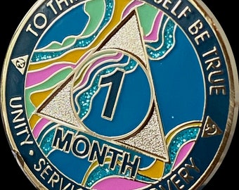 May include: Gold-toned coin with a blue background and a white triangle. The triangle has a colourful design with pink, green, and yellow accents. The coin has the text "To thine own self be true" and "Unity Service Recovery" around the edge. The centre of the coin has a blue circle with the number "1" and the word "Month" in white.