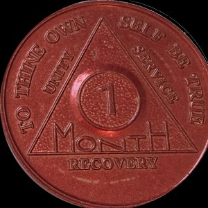 May include: A red metal coin with a triangle design and the words "To thine own self be true" and "Unity, Service" inscribed around the triangle. The center of the coin has a circle with the number "1" and the words "Month Recovery".