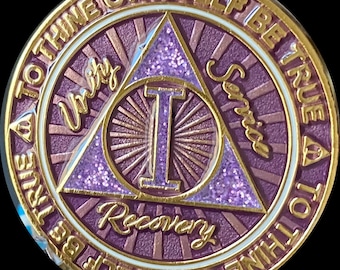 May include: A gold-colored coin with a purple triangle in the center. The triangle has a large gold letter "I" in the center and the words "Unity", "Service", and "Recovery" written around the outside. The coin has the words "To Thine Own Self Be True" written around the outside of the triangle.